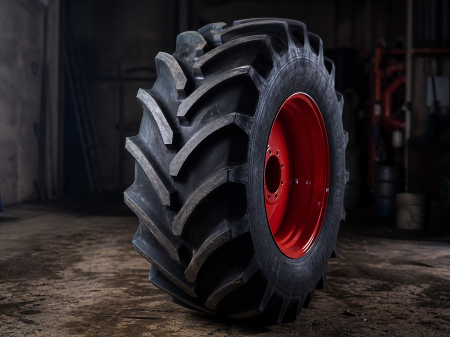 Pneu de tracteur neuf sur sa jante rouge dans l'atelier